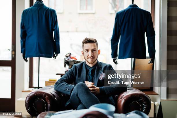 portrait of menswear store owner sitting in armchair - leather suit stock pictures, royalty-free photos & images