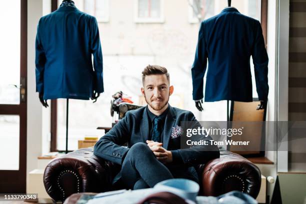 portrait of menswear store owner sitting in armchair - personal tailor stock pictures, royalty-free photos & images