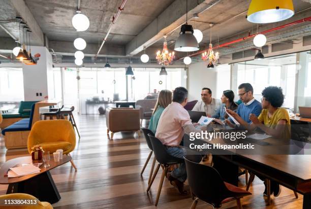 multi ethnic group of professionals at a coworking office in a meeting discussing something - new business stock pictures, royalty-free photos & images
