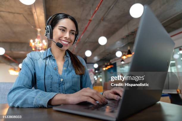 beautiful woman on a virtual meeting using her laptop and headset smiling - one woman only videos stock pictures, royalty-free photos & images