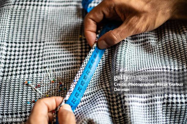 a man's hands measuring the textile with tape measure. sewing items; fabric, tape measure, ball head sewing needles. - measuring potential business stock pictures, royalty-free photos & images