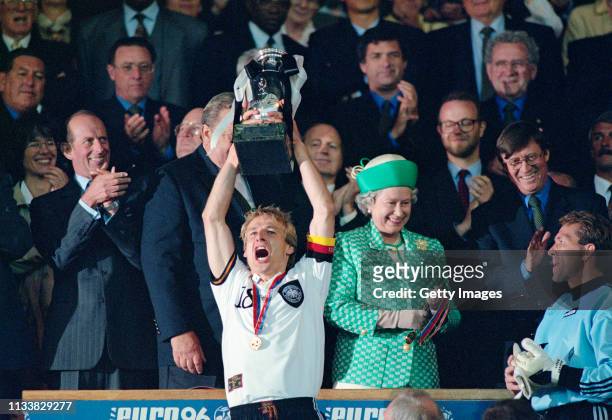 Germany captain Jurgen Klinsmann lifts the trophy as Her Majesty Queen Elizabeth II smiles and goalkeeper Andreas Kopke looks on after the 1996 UEFA...