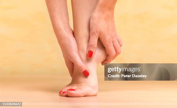 massaging sore foot - hallux valgus foto e immagini stock