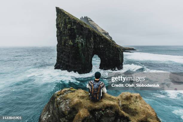 homme en chandail tricoté regardant la vue de l'arche de drangarnir dans les îles féroé - faroe islands photos et images de collection