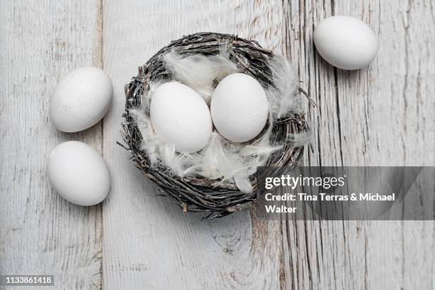 eggs in nest on white wooden background. easter. - osterkorb stock pictures, royalty-free photos & images