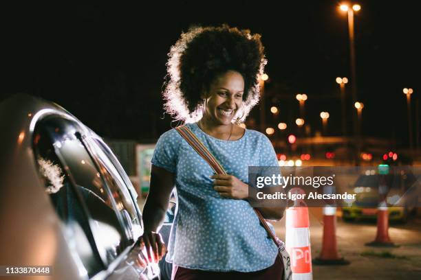 woman smiling next to the car - pregnant woman car stock pictures, royalty-free photos & images