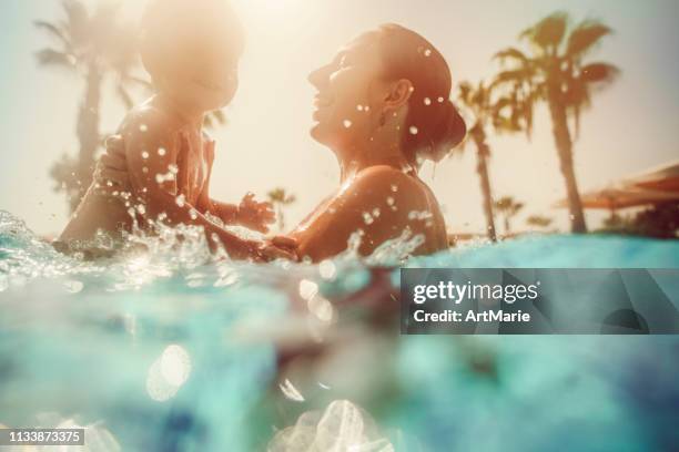 madre con bambino che si diverte in piscina al tramonto - family pool foto e immagini stock