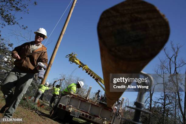 Crew members from Central Alabama Electric Cooperative rebuild a power pole in an area that was damaged by a tornado touchdown March 5, 2019 in...