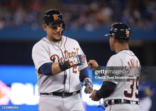 Miguel Cabrera of the Detroit Tigers is congratulated by first base coach Ramon Santiago after hitting a single in the third inning during MLB game...