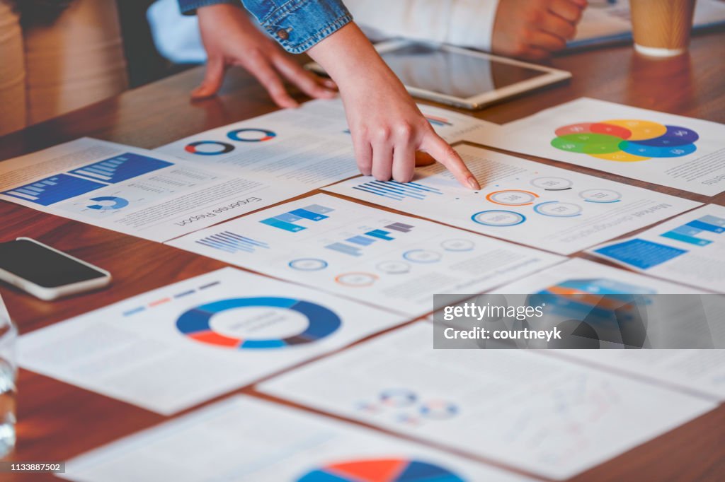 Paperwork and hands on a board room table at a business presentation or seminar.