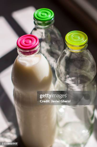 botellas de vidrio con leche y vacías - estilo de vida saludable stock-fotos und bilder