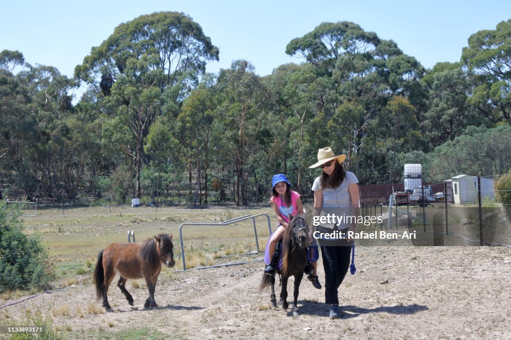 Horse trainer leading a young girl on a pony horse
