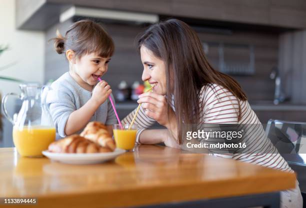 gelukkige moeder en dochter drinken sap samen - family orange juice stockfoto's en -beelden