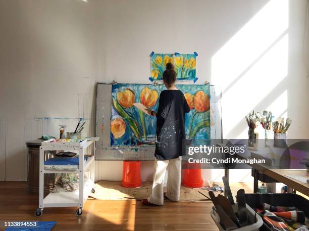 view from behind of an artist working on large paintings - kunstatelier stockfoto's en -beelden