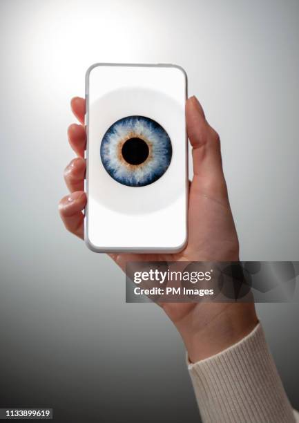 woman's hand holding cell phone with eye on screen - paranoia 2013 film stock-fotos und bilder