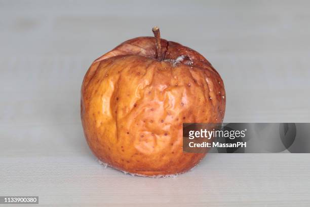 rotting apple with wrinkles and mould - brown apple stock pictures, royalty-free photos & images