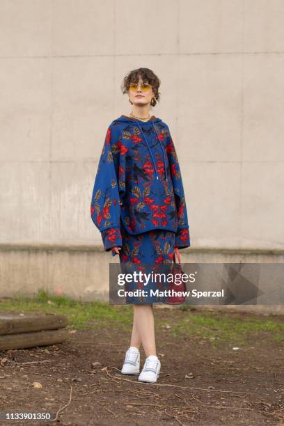 Chloe Hill is seen on the street attending Lacoste during Paris Fashion Week AW19 wearing blue/red floral pattern outfit with red bag and white...