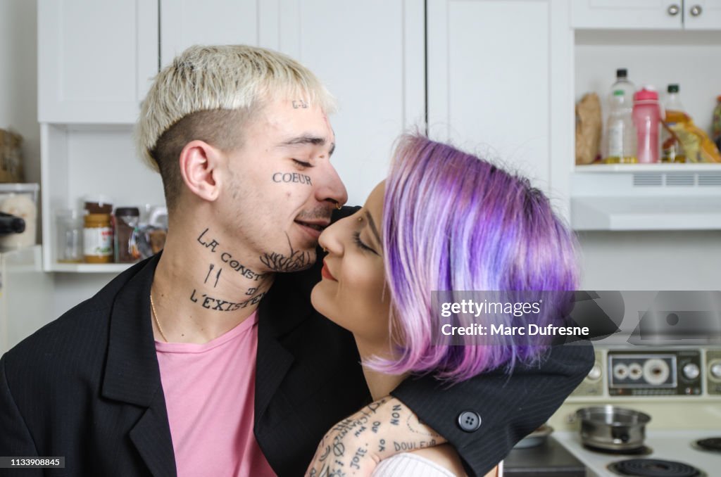 Young tattooed couple posing in their kitchen