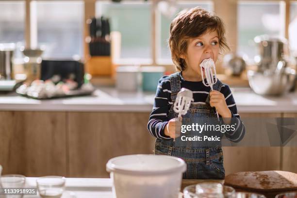 cute kid tasting whipped cream of egg beater - messy cake stock pictures, royalty-free photos & images