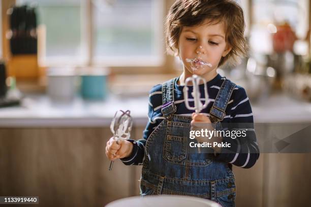 cute kid tasting whipped cream of egg beater - lamber imagens e fotografias de stock