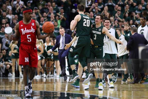 Matt McQuaid of the Michigan State Spartans celebrates a second half three point basket with teammates behind Glynn Watson Jr. #5 of the Nebraska...