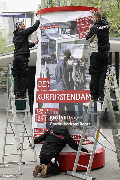 Workers sticking a large poster on a advertising column that shows the '125 years Kurfuerstendamm anniversary' at the Kurfuerstendamm on May 2, 2011...