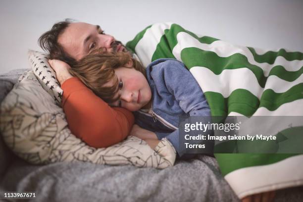 Dad and toddler trying to have a nap in the sofa