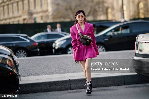 Mademoiselle Yulia wears a pink blazer jacket pleated dress, a Vuitton monogram fanny pack bag, earrings, sunglasses, outside Louis Vuitton, during...