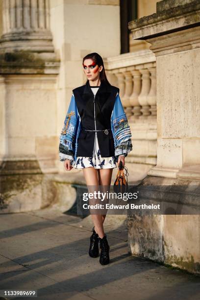 Teddy Quinlivan wears a black vest, a ruffled dress with blue sleeves, a Vuitton bag, black shoes, outside Louis Vuitton, during Paris Fashion Week...