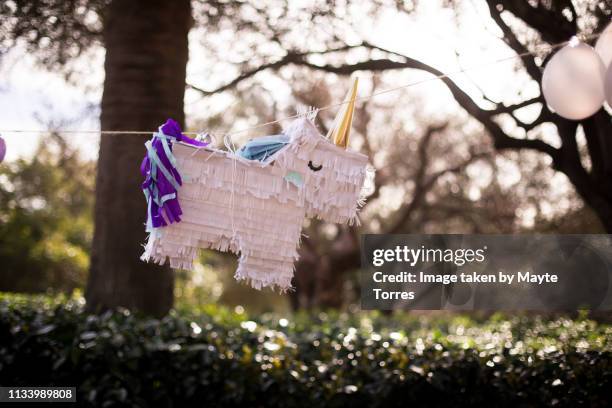 unicorn pinata in the park - piñata stock-fotos und bilder