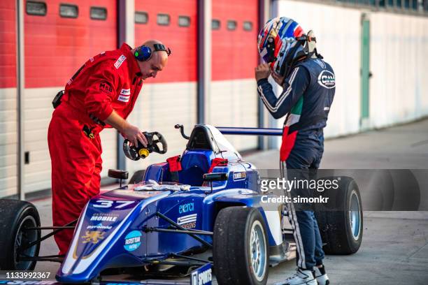 pit crew member holding steering wheel - pit stop stock pictures, royalty-free photos & images