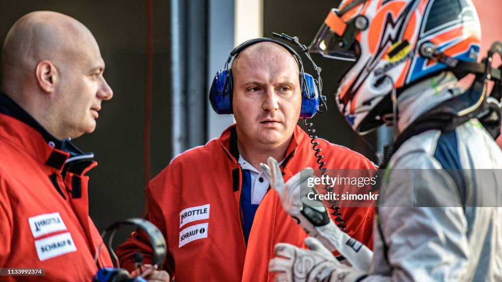 Pilote de formule parlant avec l'équipe de course