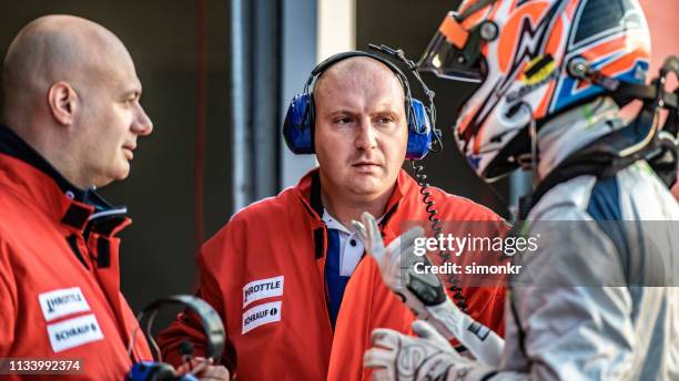 formula driver talking with racing team - pitstop stock pictures, royalty-free photos & images