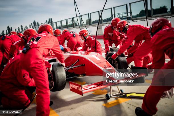 racing team working at pit stop - car racing helmet stock pictures, royalty-free photos & images