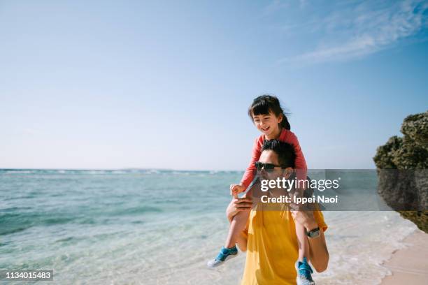 father carrying little girl on shoulders on tropical beach, okinawa, japan - asian on beach stock pictures, royalty-free photos & images