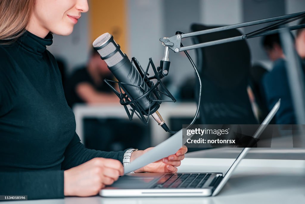 Young woman recording a podcast in a studio, close-up.
