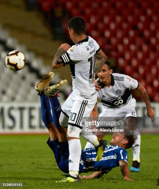 William Mendieta and Willian Candia of Club Olimpia compete for the ball with Hernan Bernardello of Godoy Cruz during a group C match between Godoy...