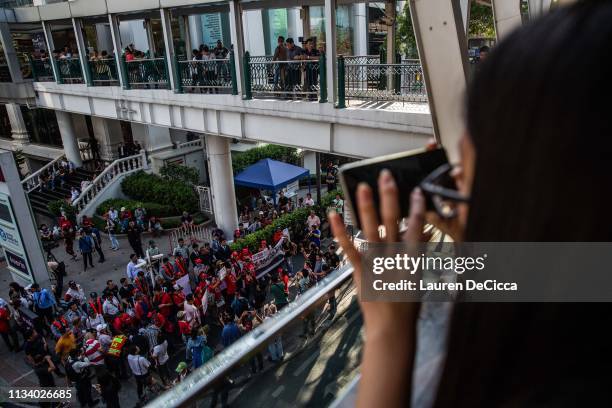 Onlookers watch Thailand's "Red Shirts", a group which began in support of Thaksin Shinawatra and against the military government, as they protest at...