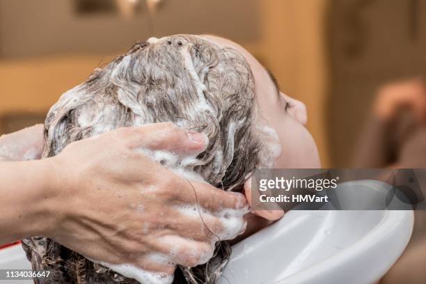 girl having her hair washed by hairdresser - hairdresser washing hair stock pictures, royalty-free photos & images