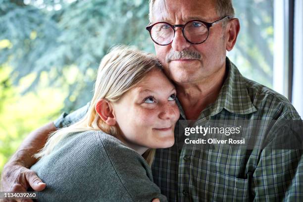 grandfather hugging adult granddaughter at the window - old man young woman stockfoto's en -beelden