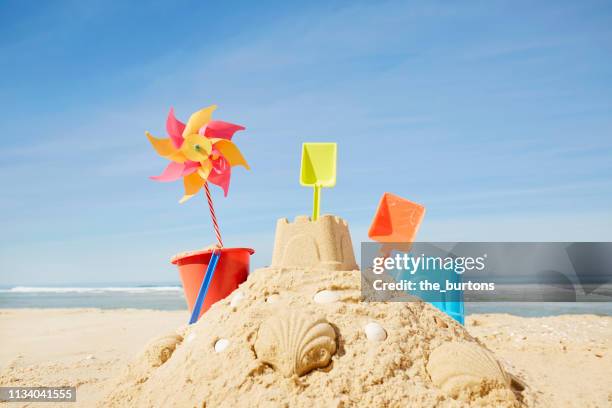 sandcastle with colorful sand toys and pinwheel on the beach - zandkasteel stockfoto's en -beelden