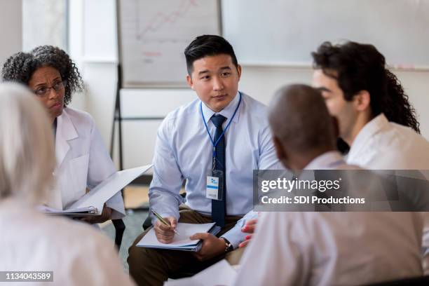 coworkers listen and take notes during medical staff meeting - conference table stock pictures, royalty-free photos & images