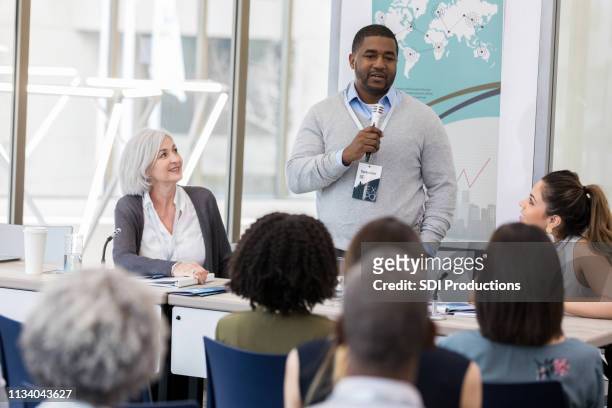 confident mid adult businessman speaks during conference - to assemble world stock pictures, royalty-free photos & images