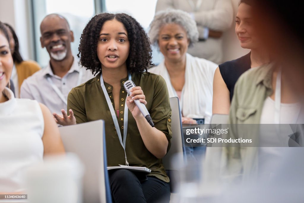 Junge Geschäftsfrau stellt während des Seminars Fragen