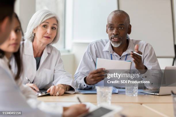 besorgte krankenhausverwalter spricht mit medizinischem personal - boardroom ipad stock-fotos und bilder