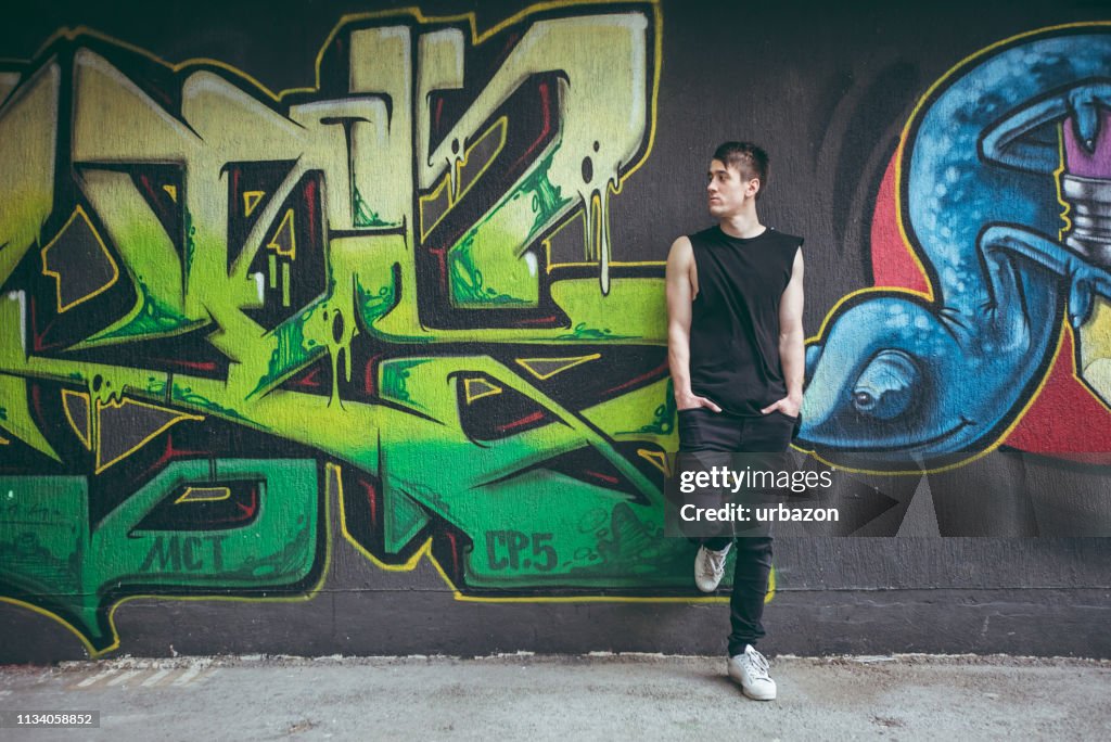 Man leaning on graffiti wall