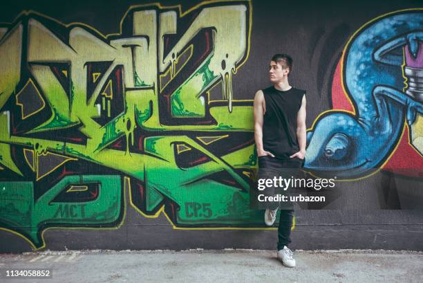 man leaning on graffiti wall - white rapper stock pictures, royalty-free photos & images