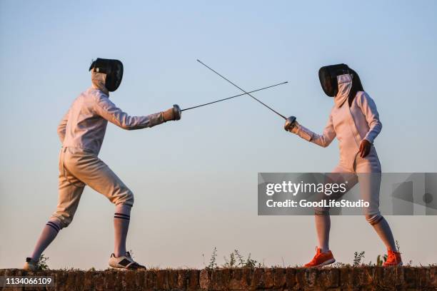 jonge man en vrouw schermen - duelleren stockfoto's en -beelden