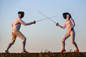 Young man and woman fencing