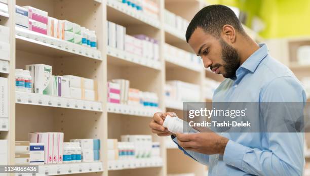 beard man choosing supplement in drugstore - probiotic stock pictures, royalty-free photos & images